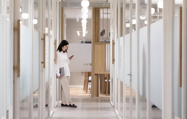 Modern office hallway with professional woman using smartphone